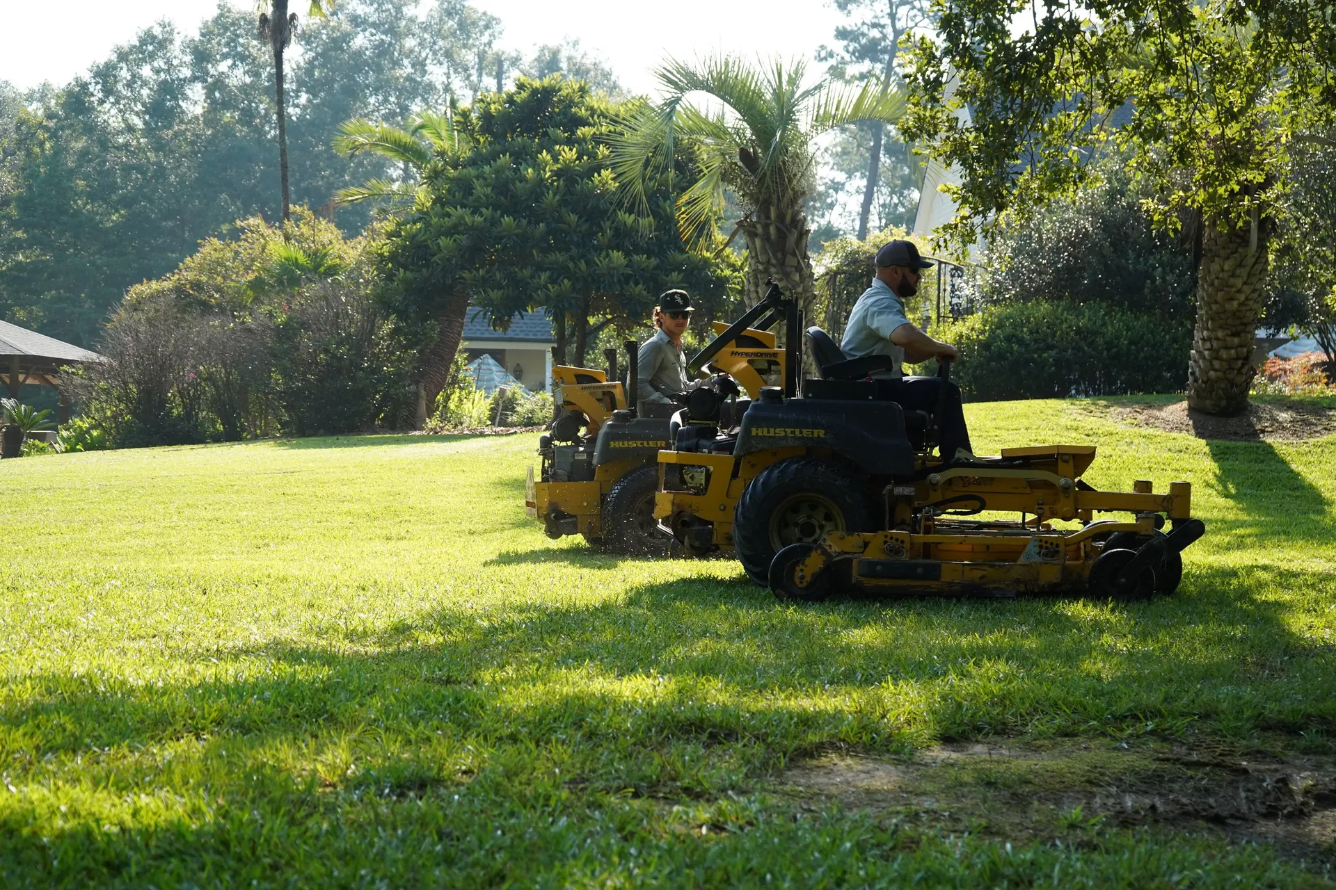Commercial mowing crew cutting turf at a Baton Rouge office property during the growing season